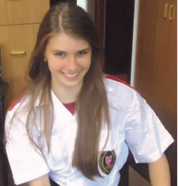 Elisabeth Hirmer smiling in a white care uniform.