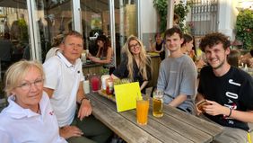 Mehrere Menschen sitzen an einem Tisch in einem Lokal.