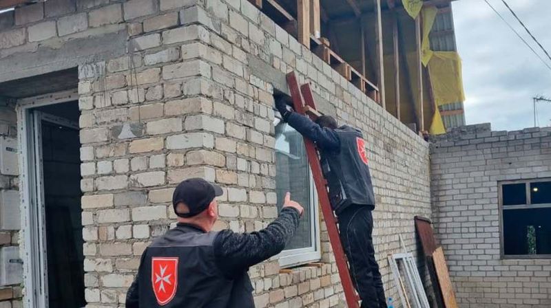Zwei Männer setzen ein neues Fenster in ein Haus ein.