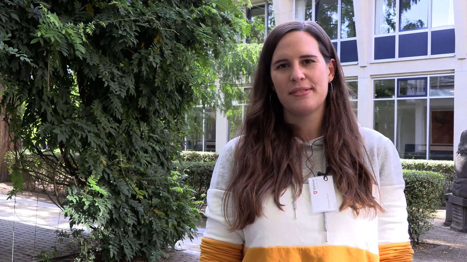 Eine junge Frau, die ehrenamtlich für den Malteser Hospizdienst arbeitet, steht draußen und schaut in die Kamera.