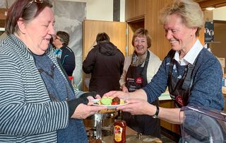 Eine Frau schenkt einer anderen Frau eine warme Mahlzeit aus.