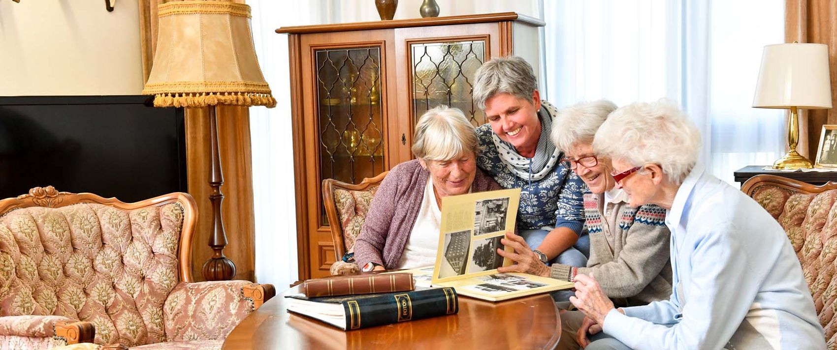 Vier Frauen sitzen auf dem Sofa und schauen sich ein Fotoalbum an