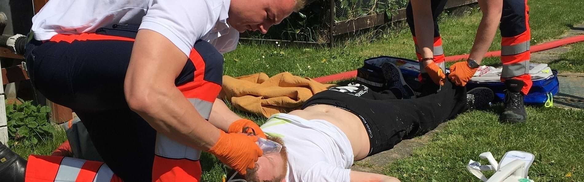 Zwei Sanitäter der Malteser versorgen einen am Boden liegenden Mann. 