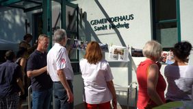 Menschen stehen vor dem Gemeindehaus Sankt Hedwig in Görlitz beisammen und reden.
