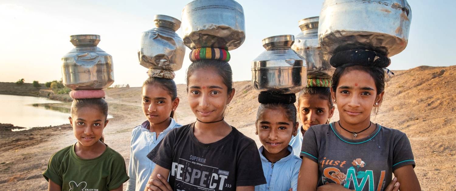 Eine Gruppe von Frauen in Indien, die Blechdosen auf dem Kopf tragen