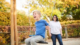 Ein kleiner Junge wird von einer Frau geschaukelt.