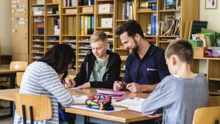 Mitarbeiter unterstützt Kind in Schule