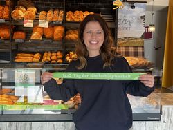 Eine Malteserin mit einem grünen Band vor der Bäckertheke