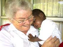 A care worker holds a child in her arms.
