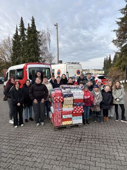 Die Kinder- und Jugendgruppe posiert hinter der Palette, auf die sie die 117 Schuhkartons gestapelt haben