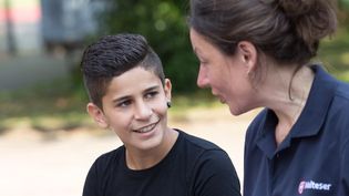 Eine junge Malteser Integrationslotsin unterhält sich mit einem Jungen.