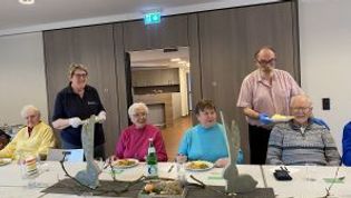 Helfer servieren den Gästen den Hauptgang an einen geschmückten Tisch