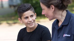 Eine junge Malteser Integrationslotsin unterhält sich mit einem Jungen.