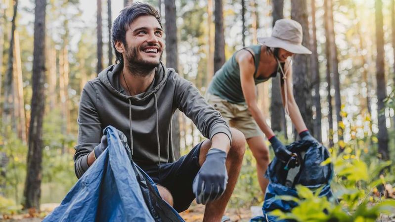 Ein junger Mann und eine Frau sammeln Müll in einem Wald