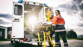 Malteser Rettungsdienstmitarbeitende verladen Krankenliege in Rettungswagen.