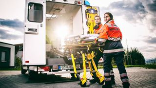 Malteser Rettungsdienstmitarbeiter tragen eine Rettungswagen Liege.