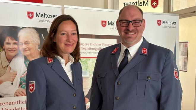 Eine Frau und ein Mann in Malteser Dienstbekleidung blicken freundlich in die Kamera.