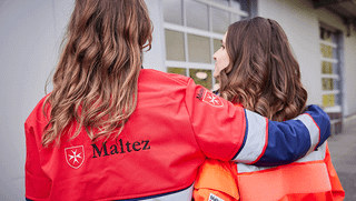 Zwei Frauen aus dem Malteser Volunteers-Programm umarmen sich. 