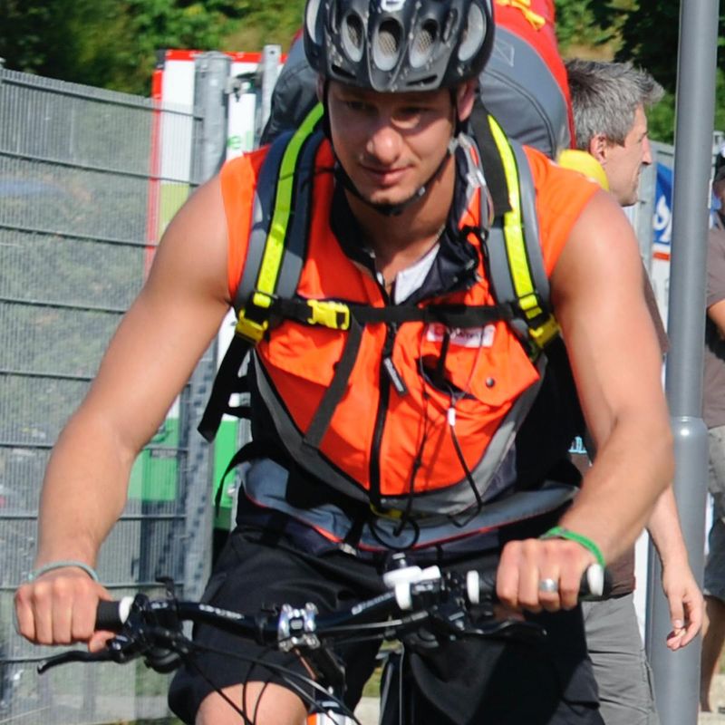 Junger Mann auf einem Fahrrad mit einer signalfarbenen Weste.