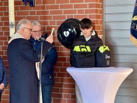 Pastor Joseph Pikos (l.) segnet die Defibrillatoren auf dem Vereinsgelände der Bruderschaft. Mit im Bild sind Schülerprinz Leo Segschneider (r.) sowie Jakob Flohr (Mitte).