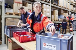 Frau mit Packkiste vor Regal