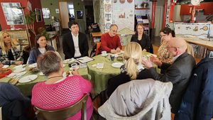 Menschen sitzen an einem Tisch und sprechen miteinander.