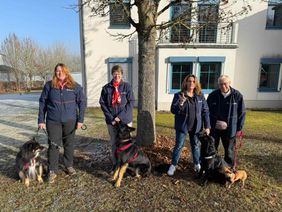 Vier Helferinnen des Besuchs- und Begleitungsdienstes stehen vor einem Gebäude mit jeweils einem Hund