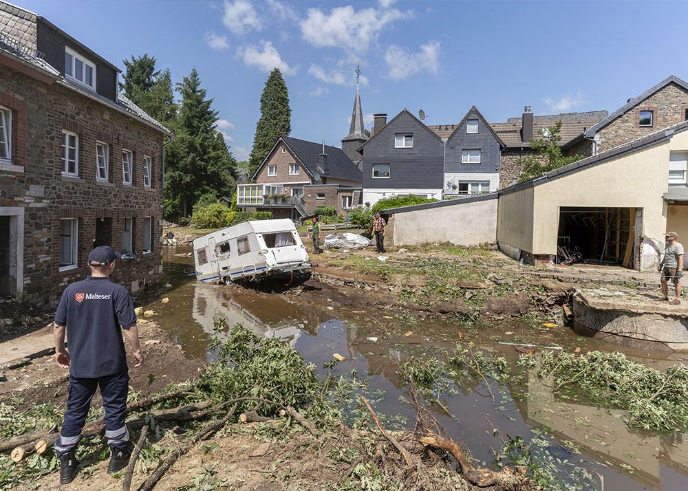 Mann steht vor Trümmern des Hochwassers