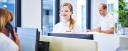 Frau mit Headset sitzt vor dem Computer.