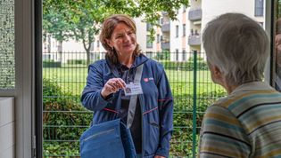 Ältere Dame öffnet die Haustür für die Mitarbeiterin der Malteser. 