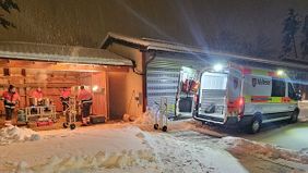 mehrere Menschen stehen an großen Küchengeräten in einer offenen Halle hinter einem verschneiten Hof