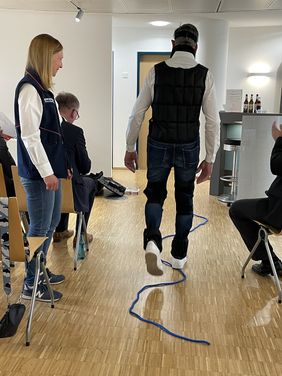 Ein Freiwilliger versucht, mit dem Alterssimulationsanzug entlang eines Seils zu laufen