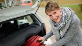 Eine Frau steht am Kofferraum ihres Autos.