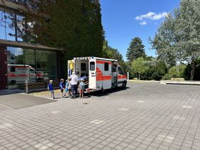 Kinder vor einem offenen Rettungswagen, um diesen gleich zu erkunden.