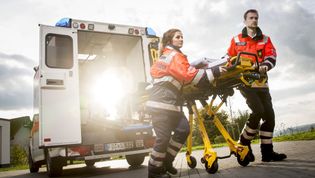 Zwei Rettungssanitäter mit einer Krankentrage vor einem Krankenwagen