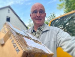 Pfarrer Stefan Krönung erhält ein Postpaket, das Sachspenden für die Ukrainehilfe enthält