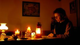 Eine Frau liest beim Schein von Kerzen und Laternen