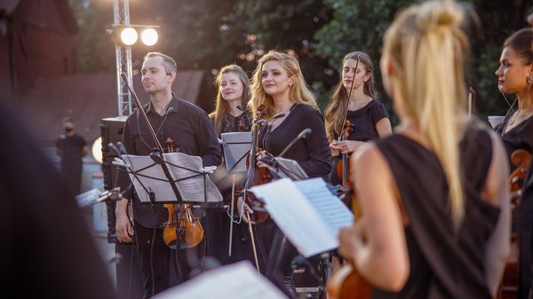 Musikerinnen und Musiker eines Orchesters bei einem abendlichen Auftritt im Freien 