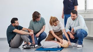 Beim Erste-Hilfe-Kurs der Malteser: Eine Gruppe übt an einer Puppe die Herzdruckmassage.