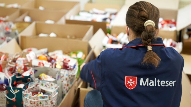 Eine junge Frau von den Maltesern packt Geschenktüten.