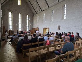 Gruppe von Menschen sitzen in einer Klosterkirche