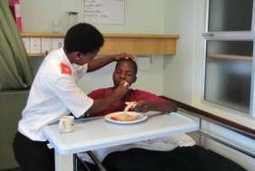 A nurse helps a patient eat at the bedside.
