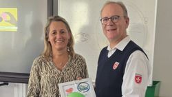 Eine Frau und ein Mann in Malteser Dienstbekleidung mit einer Urkunde