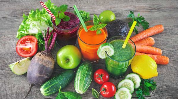 Bunte Smoothies umringt von buntem Gemüse und Obst