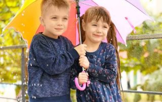 Zwei Kinder stehen unter einem Schirm