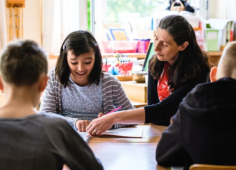Eine Schulbegleiterin der Malteser betreut eine Schülerin beim Lernen.