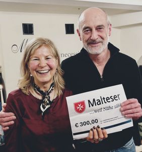 Eine Frau übergibt einem Mann einen Spendenscheck