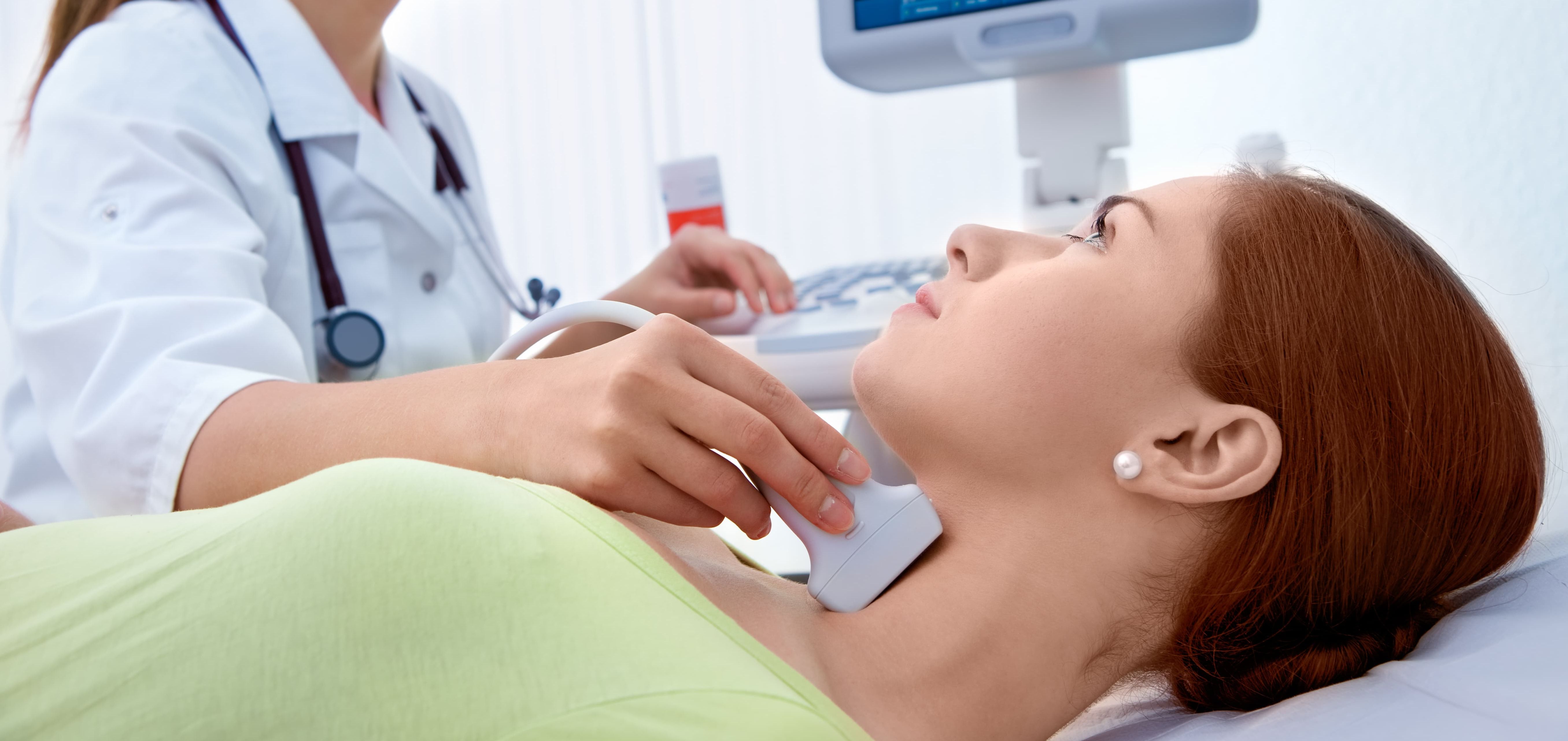 Medizinische Fachkraft führt Ultraschalluntersuchung am Hals bei einer Patientin durch.