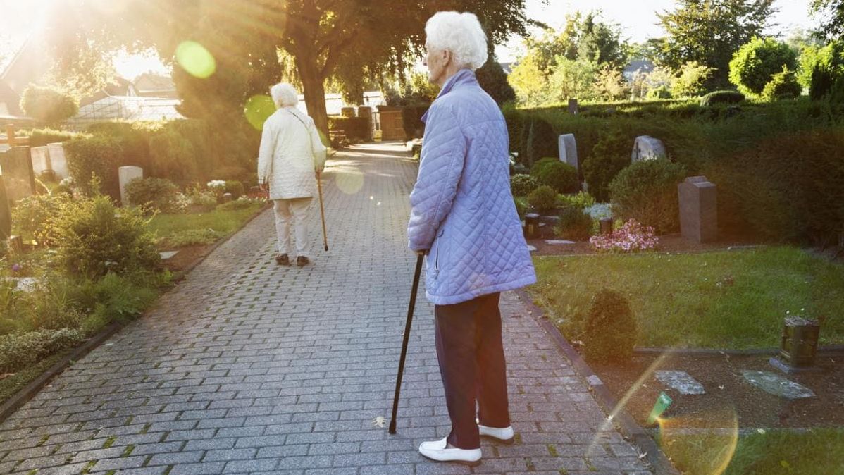 Zwei ältere Damen, die einen Friedhof besuchen.