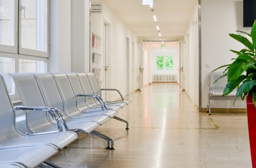 Heller Wartebereich in der Terminambulanz mit Fensterfront, weißen Wänden und Sitzbänken aus Metall.